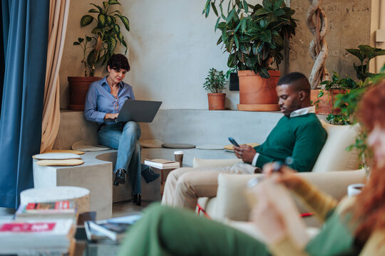 Coworkers using laptop and smart phone in modern office space