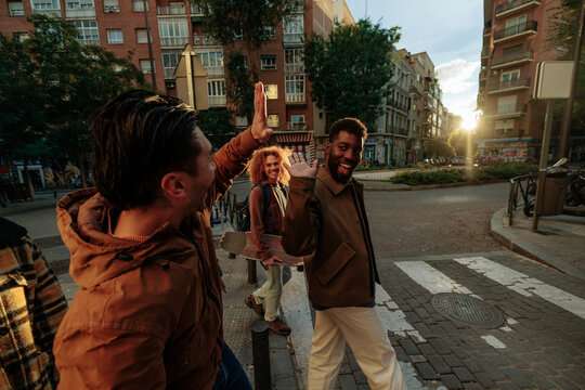 Group of friends giving high five crossing the street at sunset