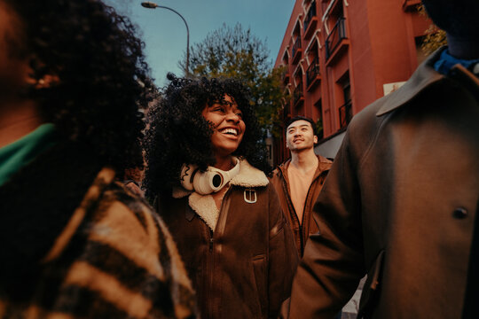 Group of young diverse friends walking and talking together in the city