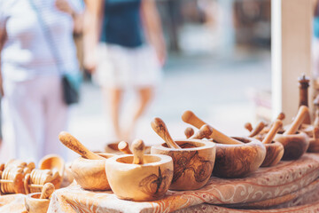 Handcrafted wooden mortar and pestle displayed at a vibrant market in summer, attracting attention from visitors exploring artisanal creations