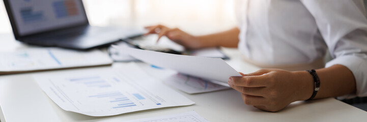 Obraz premium Businesswoman analyzing financial data and using calculator in office