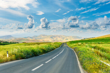 beautiful landscape of long road to amazing mountain scene from a green summer fields and hills....