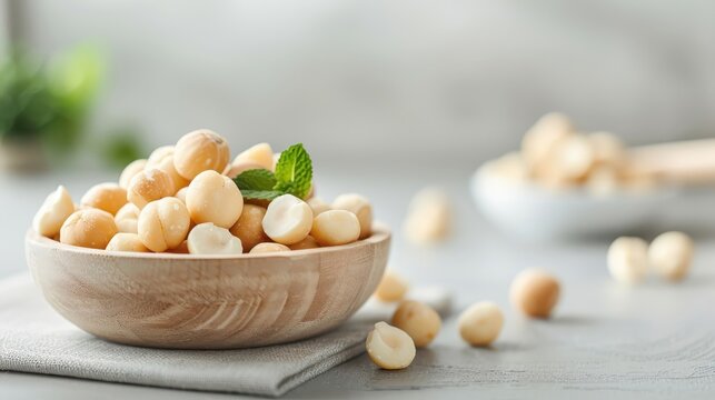 A bowl of roasted macadamia nuts with cracked shells on a rustic wooden table.
