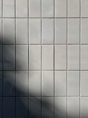 Minimalistic gray tiled wall with subtle shadow creating a clean geometric pattern