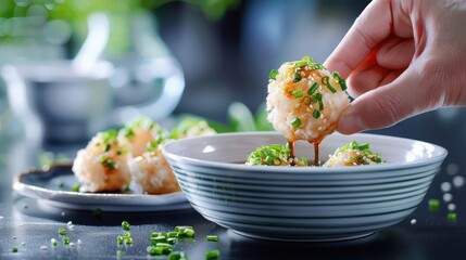 A hand dipping tempura into a bowl of ponzu sauce.