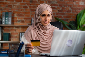 Middle Eastern Muslim woman in beige hijab working in an office