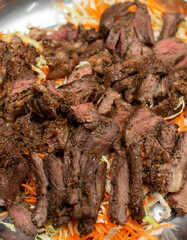Sliced beef on a tray with vegetables, close-up photo.