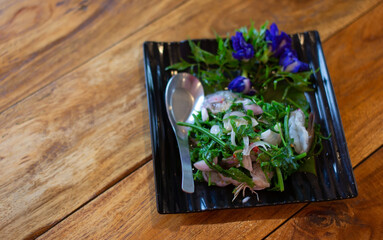 Fresh shrimp salad with asparagus in a black plate placed on the floor
