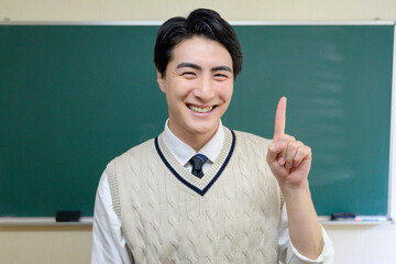 黒板の前で指をさす日本人男性