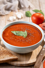 Homemade Tomato Soup in bowl with Basil on wooden table