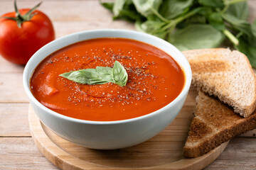 Homemade Tomato Soup in bowl with Basil on wooden table