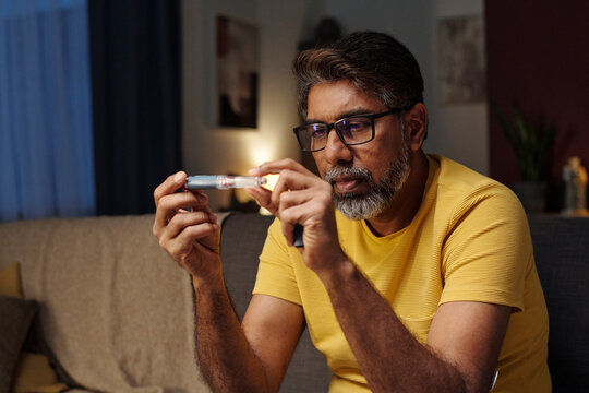 Man checking glucose level with insulin at home in evening