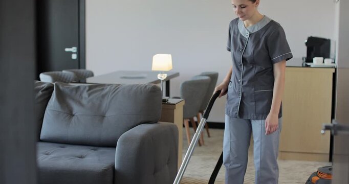 Professional housekeeper woman hovering floor in bedroom apartment in hotel while serving room. Hotel service.