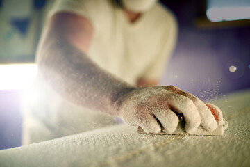 Manufacturing, hand and sanding surfboard in workshop for production process, design and creative craftsmanship. Surf, worker and man with tools for shape, polish and grinding foam with dust closeup
