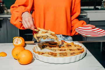 Person serving homemade mushroom pie in home kitchen with oranges