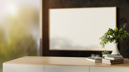 Glasses atop books and plants on wooden table in a bright room with glass wall and outside scenery.