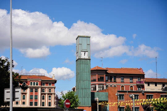 Green glass clock tower and surrounding buildings under a blue sky in Barakaldo Spain on a sunny summer day