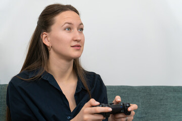 Young woman enjoying a thrilling video game session, gripping a joystick while sitting comfortably on the sofa, fully immersed in the screen and experiencing pure joy