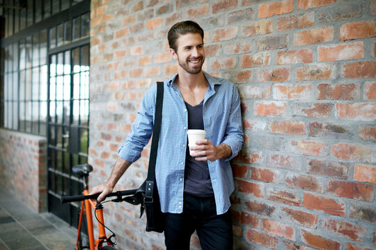 Coffee, smile and man with bicycle, travel and break with eco friendly transport. Happy person, wall and biker with herbal tea, pride and cyclist with journey, joyful and confidence in lobby - Powered by Adobe
