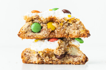 Fresh chocolate American chip cookie broken in half and decorated with multicolored candies on white background. Close up of cookies with chocolate colored candies inside