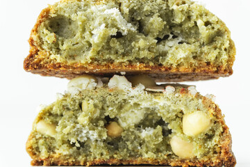 Close up of American chocolate chip cookie broken in half with matcha flavor decorated with almond nuts and matcha tea powder inside on white background.