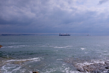 High waves in the ocean and a  big boat seen in the distance