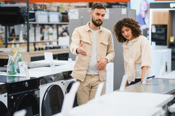 Obraz premium Couple choosing washing machine in electronics store