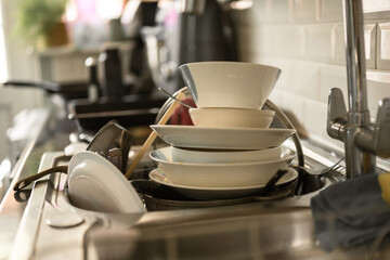 Dirty dishes in kitchen's sink, daily chores, cleaning home 