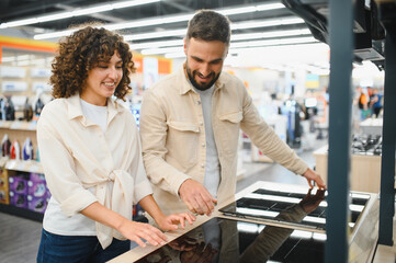 Couple choosing induction stovetop in electronics store