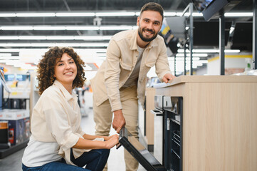 Couple choosing new oven in electronics store
