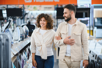 Couple choosing home appliances walking in electronics store