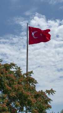 Large Turkish national flag waving in the wind at Sarayburnu Park (İBB Sarayburnu Parkı) in Istanbul, Turkey. The red flag with a white star and crescent is seen against the sky.