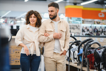 Couple choosing vacuum cleaner in electronics store