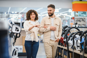 Couple choosing vacuum cleaner in electronics store