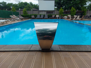 Drawing of a swimming pool, clear blue water, for relaxation, with facilities for lying and sitting, entertainment facility