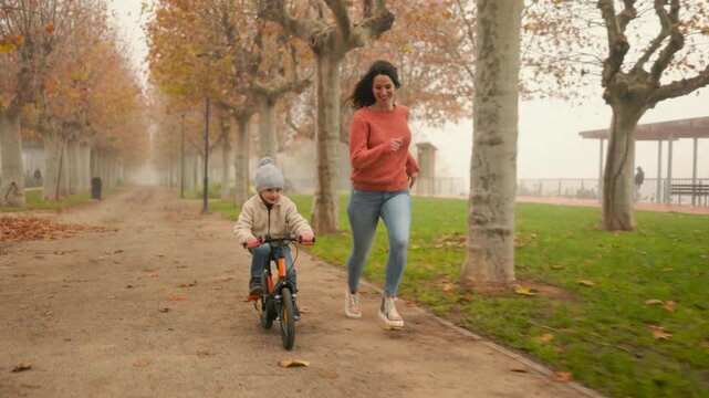Mother and son enjoying a bike ride in autumn park.