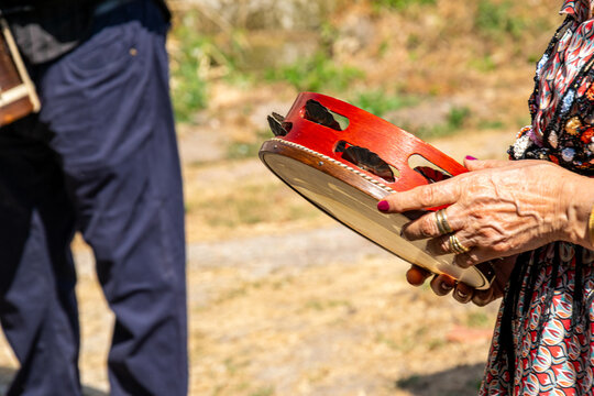 The hands of a pandeireta player with rings and painted nails.