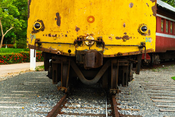 Close-up of an old locomotive and old carriages on a decommissioned railway, the paint cracked, peeled and rusted.