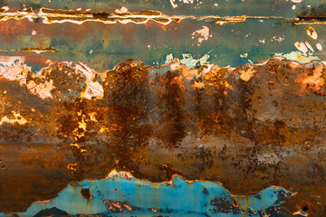 Close-up of an old locomotive and old carriages on a decommissioned railway, the paint cracked, peeled and rusted.