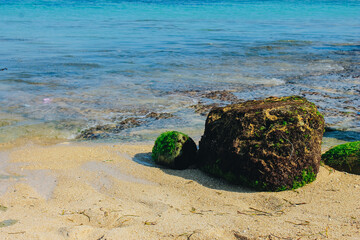 Mossy rocks and sea waves at eye level on the coast of Bali, Indonesia