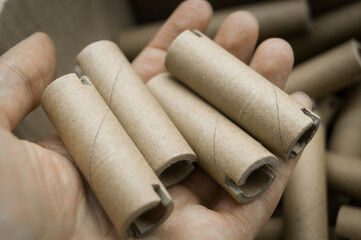 Special cardboard cores for winding paper and film tapes. Paper tubes for winding the products of printing houses. Cardboard tube on hand. Selective focus
