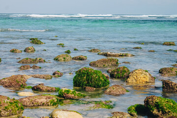 Mossy rocks and sea waves at eye level on the coast of Bali, Indonesia