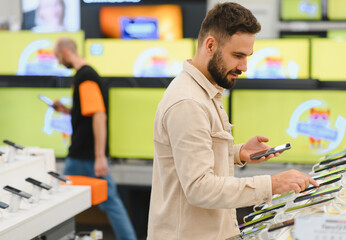 Customer comparing smartphones in electronics store using his phone
