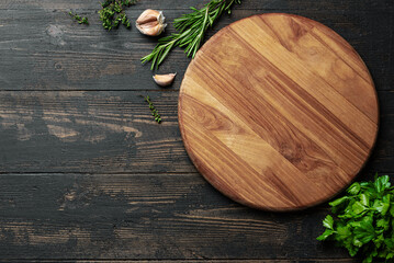 Empty wooden round platter with herbs and garlic