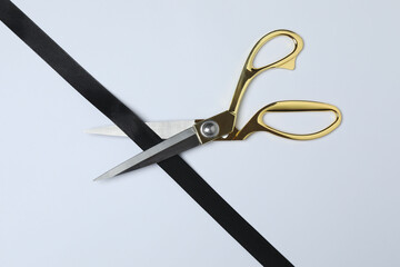 Golden scissors with ribbon on white background, flat design. Place for text.

