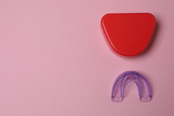 The mouthguard lies on a pink background.
