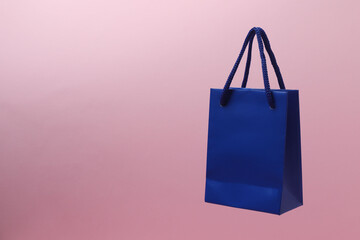 blue shopping bag with pink handle on orange background

