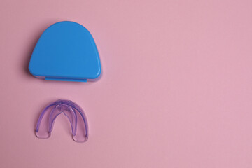 The mouthguard lies on a pink background.
