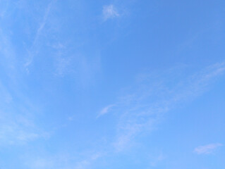A serene expanse of clear blue sky with minimal, wispy white clouds, offering a spacious and...