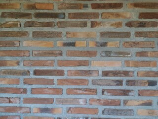 A rough, textured red brick wall with visible mortar joints, showcasing a classic and durable construction material.